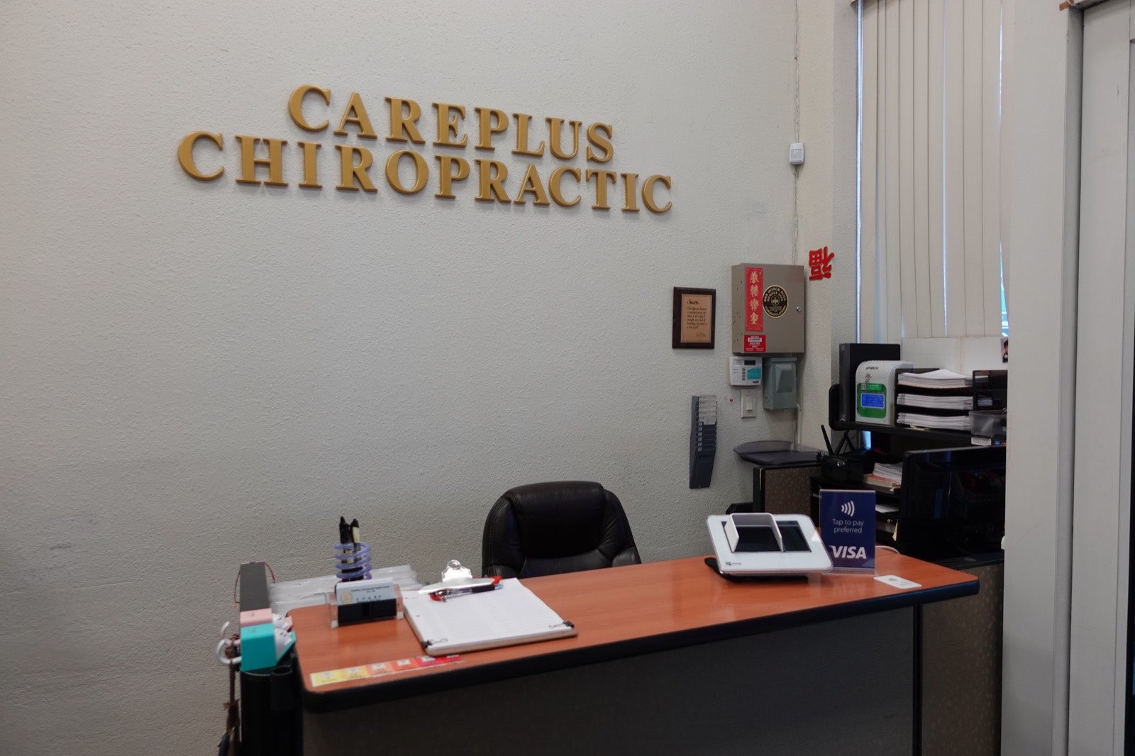 櫃台區，牆上為 CAREPLUS CHIROPRACTIC 立體字